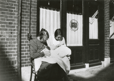 875062 Afbeelding van Petronella Siskens-Bals (1876-1930) en Jopie Siskens bezig met een naaiwerkje voor het pand Lange ...